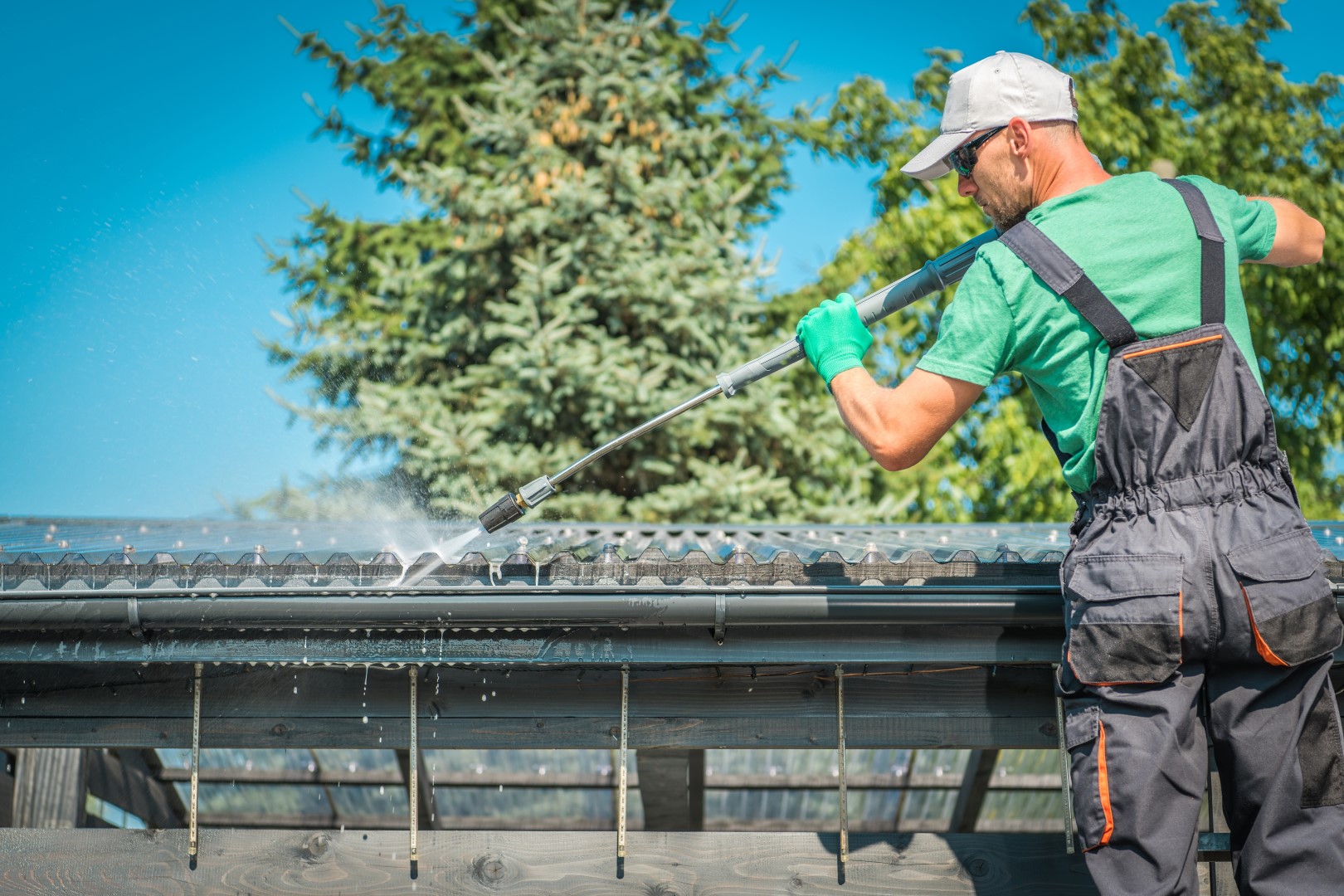 man using pressure washer for gutter cleaning