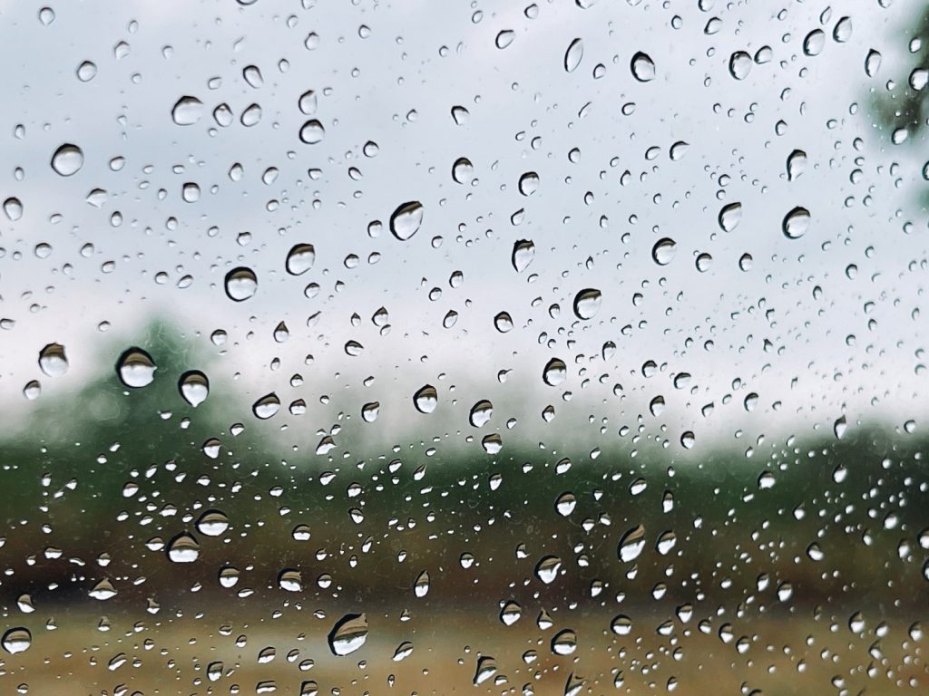 Rain droplets on a clear glass window after professional window cleaning.