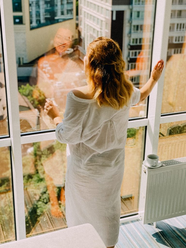 Woman enjoying sunlight through spotless windows after window cleaning.