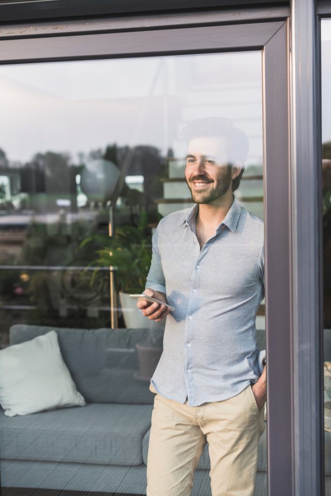 Man looking through a clean glass door after residential window cleaning in a modern home.